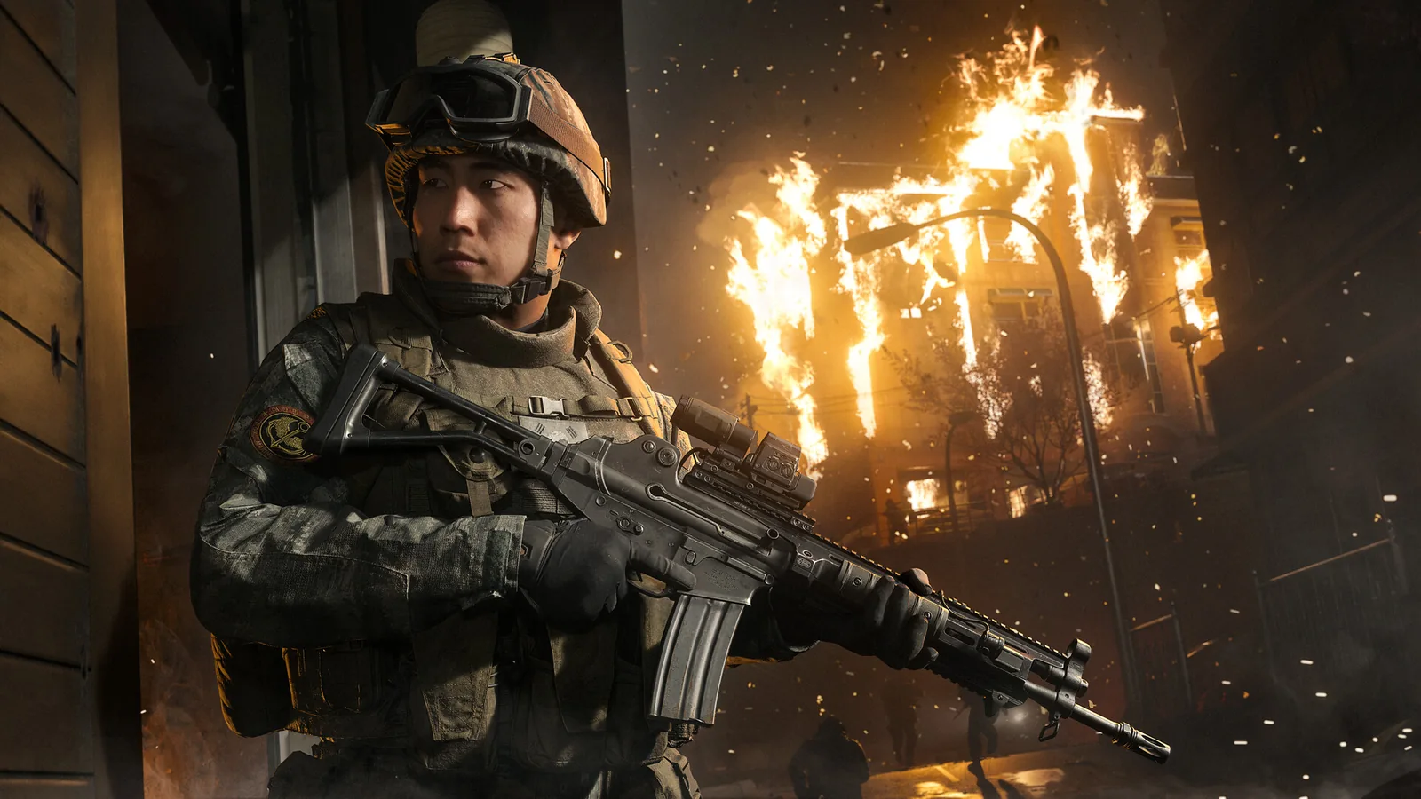 Official Modern Warfare 4 promotional scene of a soldier holding a rifle beside a burning building.